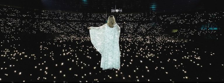 sanah w białej szacie skierowana w kierunku publiczności w hali spodka