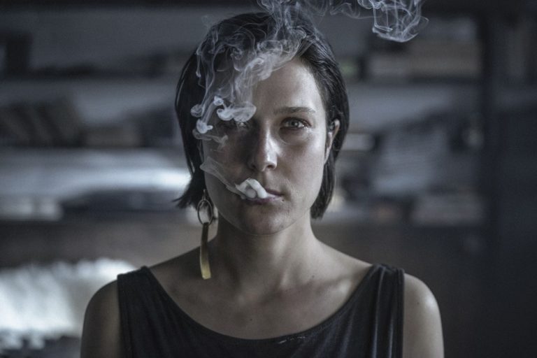 twarz kobiety wypuszczającej dym z papierosa